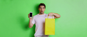 shopping bag in a hand of a man, and a smartphone in another hand