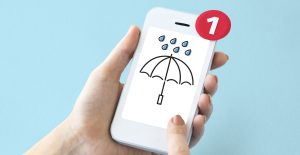 smartphone in a hand, with a weather alert on screen.